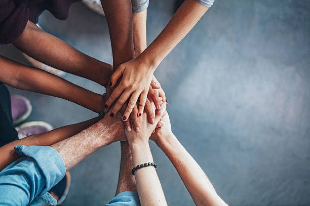 Close up top view of young people putting their hands together. Friends with stack of hands showing unity.